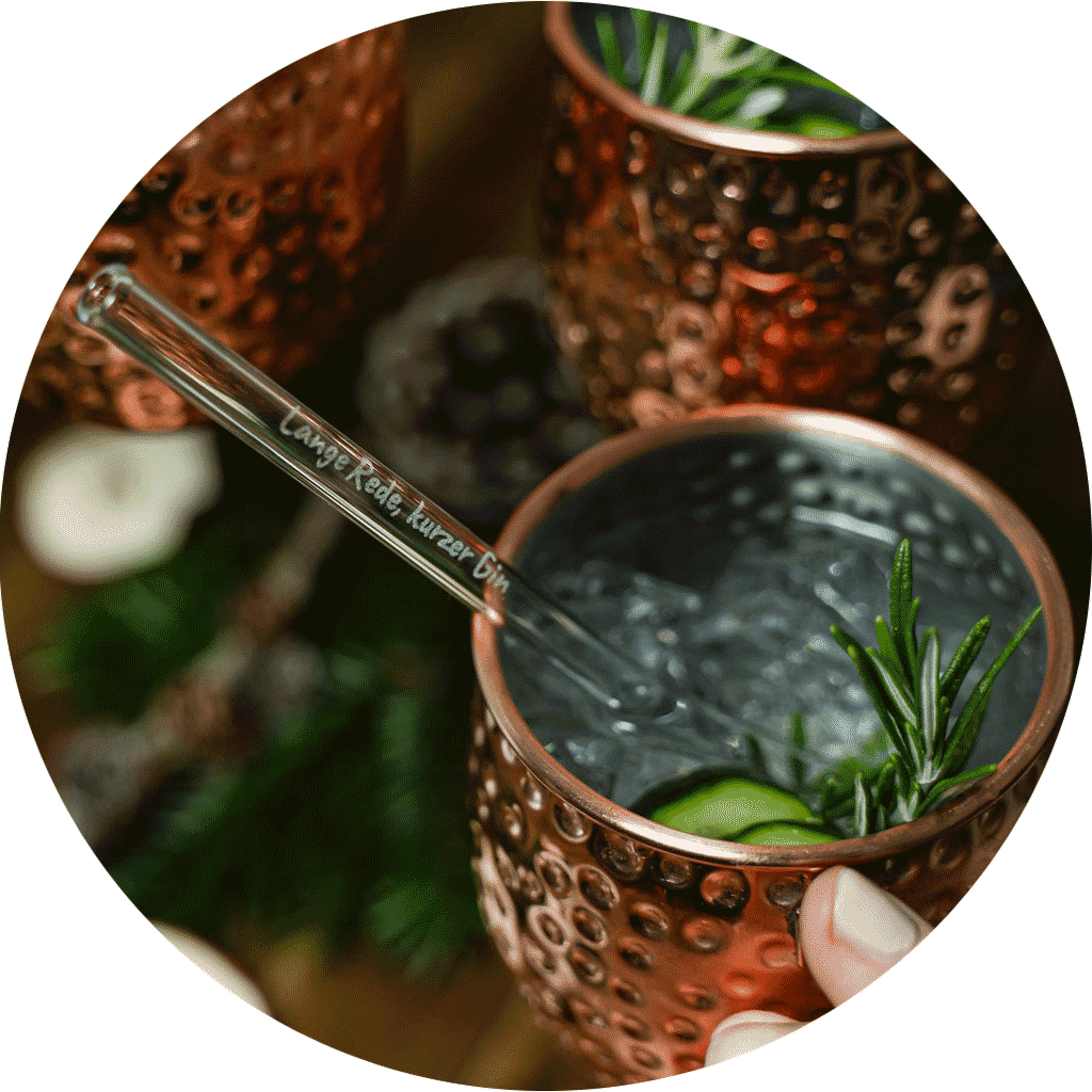Pailles en verre HALM réutilisables avec gravure personnalisée dans un verre à cocktail, comme idée cadeau durable pour les femmes.