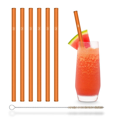 Wiederverwendbare HALM Glasstrohhalme in Neonorange neben einem Glas Wassermelonen-Saft auf einem sommerlichen Tisch.