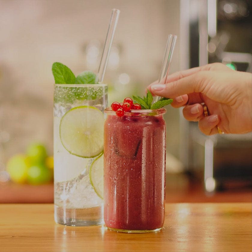 Wiederverwendbare HALM Glasstrohhalme in verschiedenen Getränken wie Smoothie und Gin Tonic auf einem Werbebanner