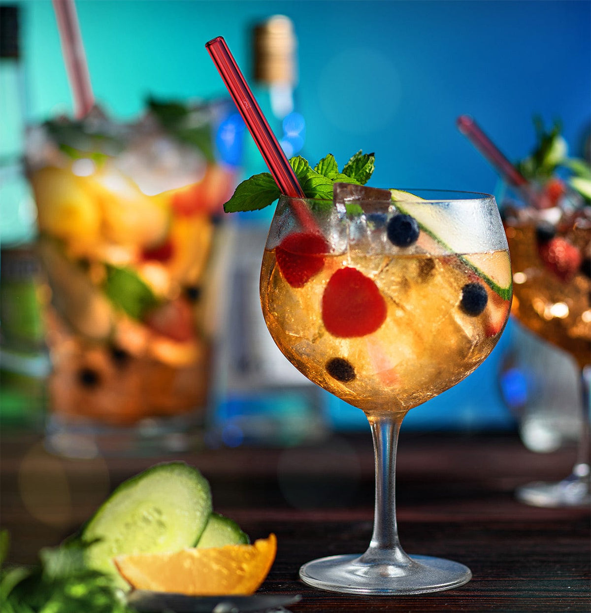 Ein erfrischender Pimms Punch mit Früchten und Minze serviert mit einem roten, wiederverwendbaren HALM Glasstrohhalm.