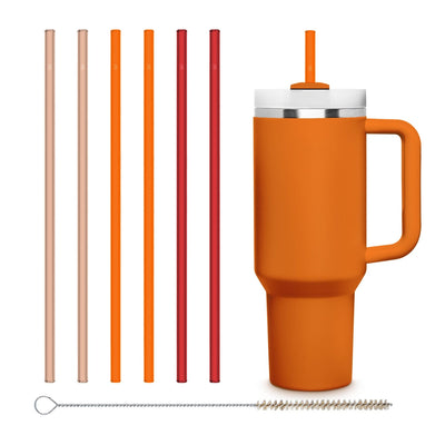 Sechs wiederverwendbare HALM Glasstrohhalme in Pink, Fuzz, Orange und Rot stecken in einem Getränk in einem orange-matten Stanley Cup.