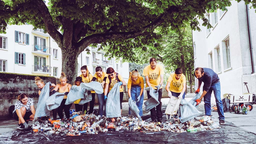 Employees of a company collect trash together at a Trash Hero cleanup event in support of the HALM Less Waste Initiative for reusable glass straws